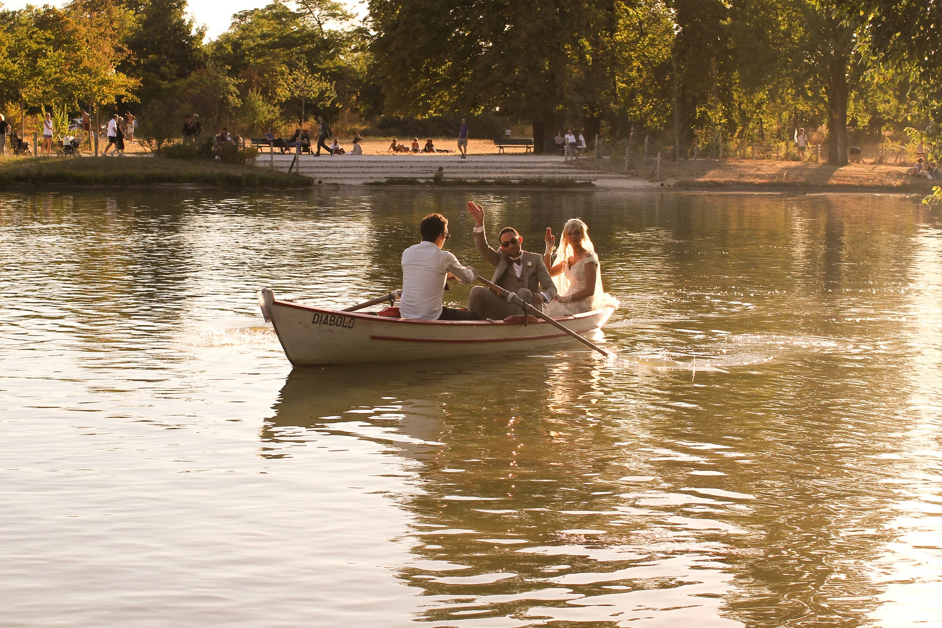 Une mariée et ses accompagnants dans une barque sur un lac à la lumière dorée