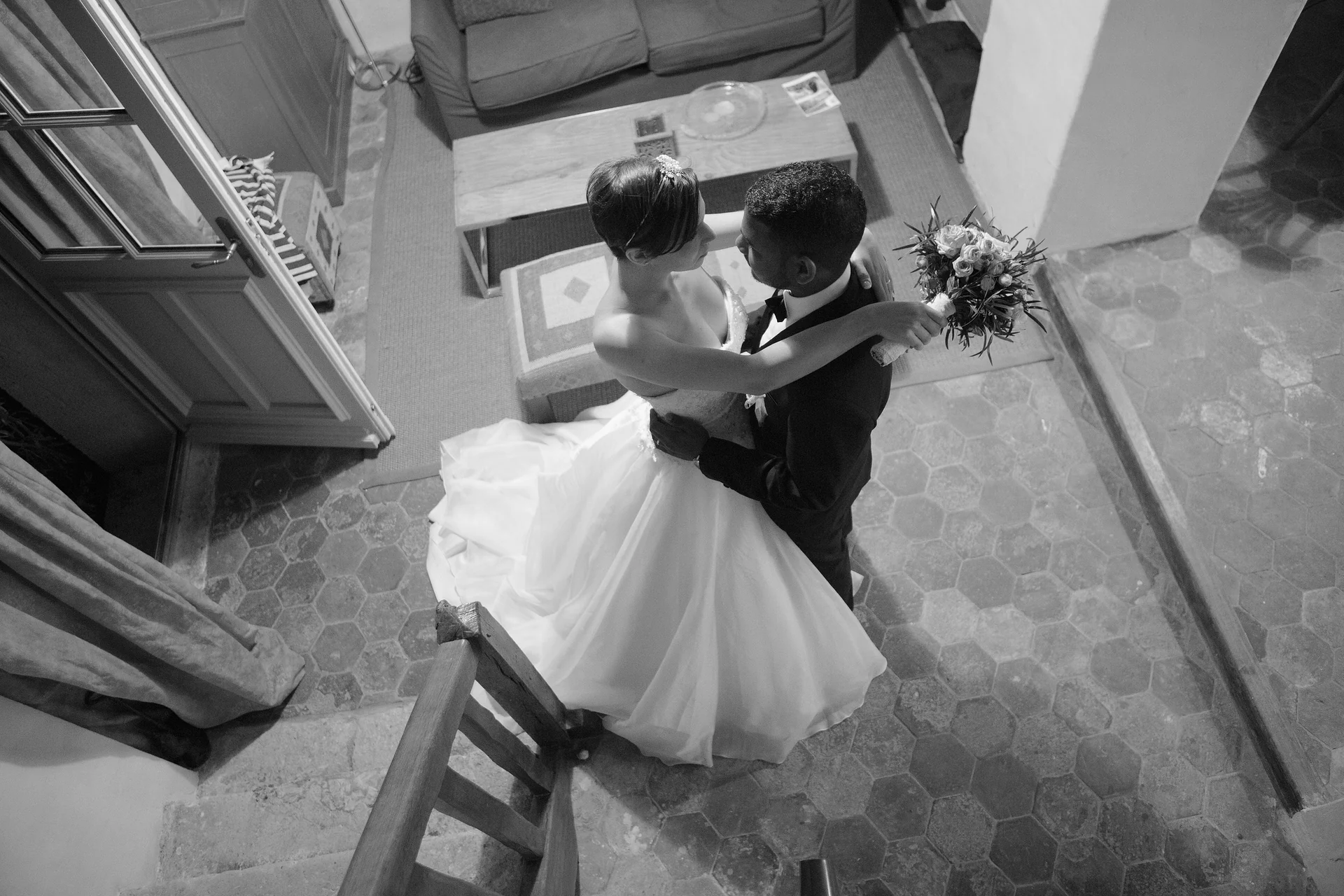 Les mariés enlacés au bas d’un escalier, photographiés en plongée en noir et blanc