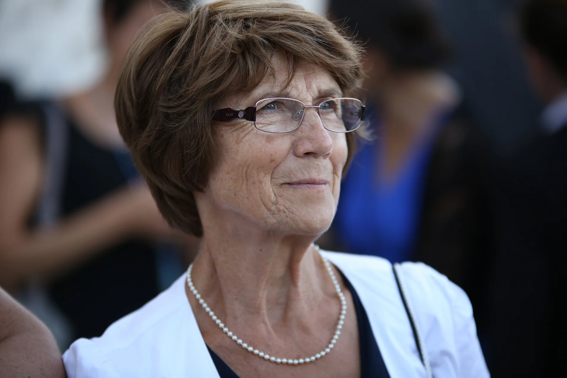 Portrait d’une invitée à lunettes et collier de perles pendant un mariage