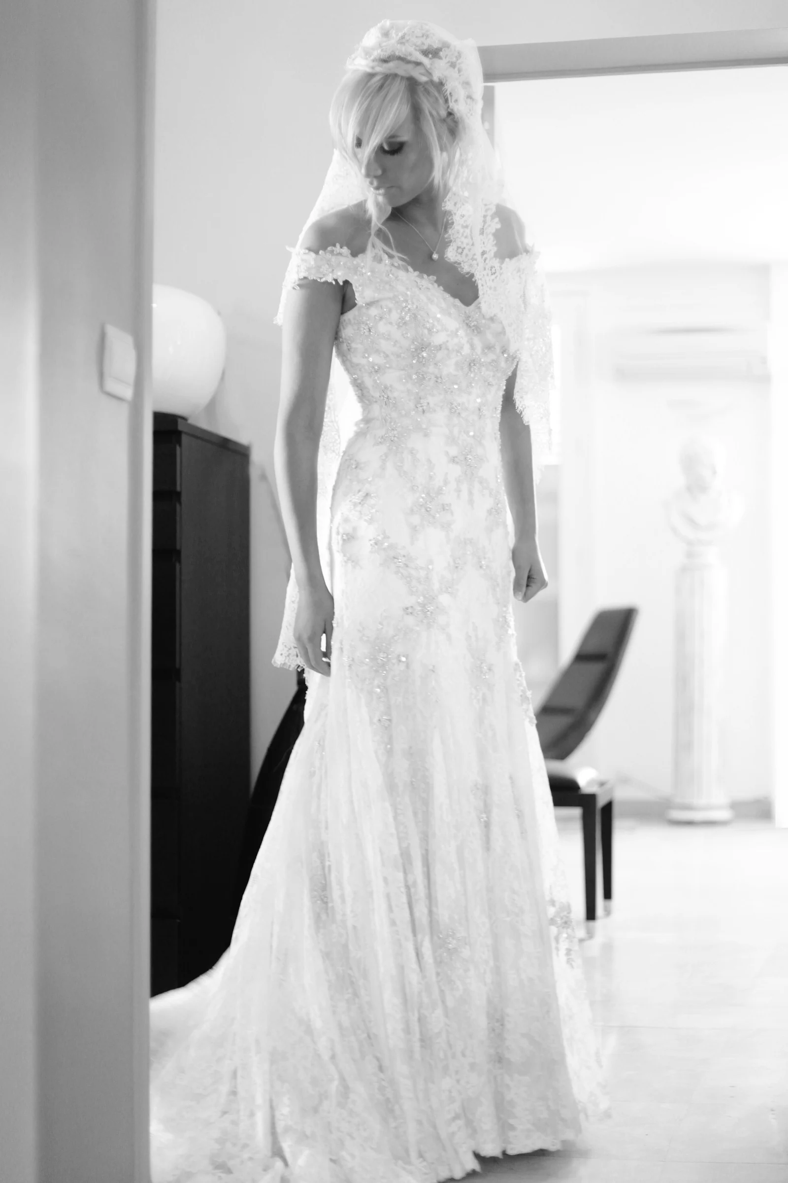 Portrait en pied d’une mariée en robe de dentelle, en noir et blanc